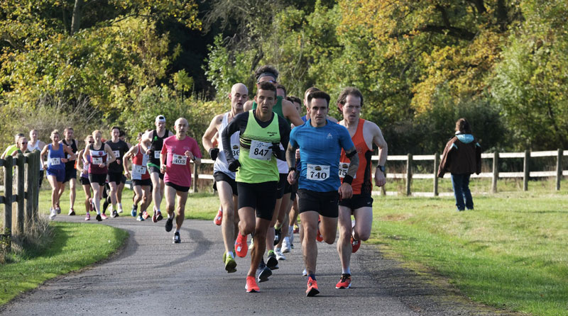 Group of people running through a park.